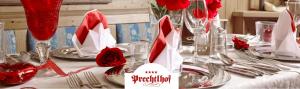 a table with red and white napkins and red roses at Hotel Prechtlhof in Althofen