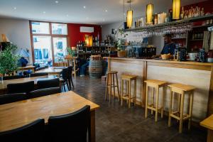 a bar with wooden tables and chairs and a man behind the counter at Hôtel Bistrot Les Tanins in Saint-Antoine +29 photos