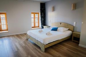a bedroom with a large bed with white sheets and blue pillows at Hôtel Bistrot Les Tanins in Saint-Antoine