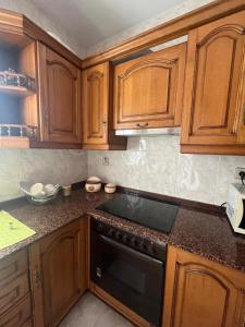 a kitchen with wooden cabinets and a black stove top oven at Rúa da Igrexa Miño in Miño +16 photos