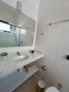 a white bathroom with a sink and a mirror at Vila dos Pinheiros 1 in Serra Negra +11 photos