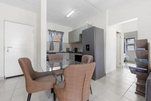 a dining room and kitchen with a glass table and chairs at Gae La Rona in Gaphatshwe