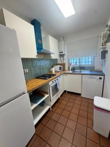 a kitchen with white appliances and a tile floor at Casa en la montaña con jacuzzi exterior y piscina in Alcántara de Júcar