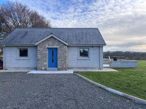a small house with a blue door in a field at Moate View Lodge in Ballymore Eustace