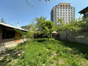 a yard with trees and a building in the background at Stay Osh in Osh