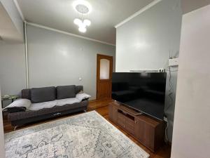 a living room with a couch and a flat screen tv at Stay Osh in Osh