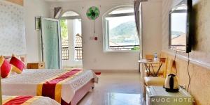 a bedroom with two beds and two windows at Bai Truoc Hotel in Vung Tau