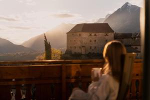 a woman sitting in a chair looking at a mountain at Hotel Starkenberg in Schenna