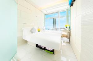 a white bedroom with a bed and a window at iclub To Kwa Wan Hotel in Hong Kong