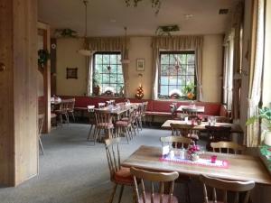 a dining room with tables and chairs and windows at Landhotel Osterlamm in Grünhain