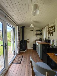 a kitchen with a table and chairs in a tiny house at Bell Nook- Shepherd's hut with a spacious wood-fired hot tub in Tonbridge