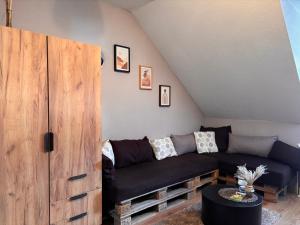 a living room with a black couch and a wooden cabinet at Päächenhof in Sinspelt