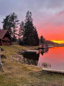 a sunset over a lake with a house and a boat at Oksa Puhkemaja in Võru +13 photos