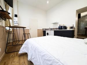a bedroom with a white bed and a kitchen at Studio Riom - Proche gare SNCF in Riom +8 photos