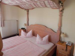 a bedroom with a bed with pink sheets and pillows at Landhotel Osterlamm in Grünhain