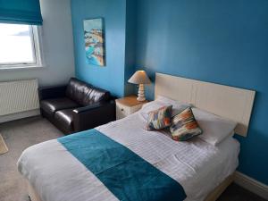 a bedroom with a bed and a leather couch at The Paris Hotel in Coverack