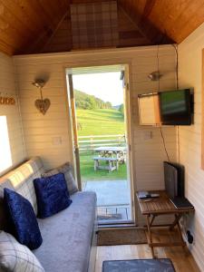 a living room with a couch and a tv and a table at The Niblet Bonnie View Glamping Cabins, Helmsley in Carlton