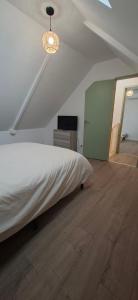 a bedroom with a white bed and a wooden floor at L'Escale Chaunoise in Chauny
