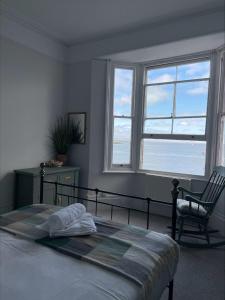 a bedroom with a bed and a chair and windows at Beds at 46, Cowes in Cowes