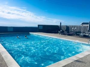 two people swimming in a large blue swimming pool at Bardsey View Holiday Park Nr New Quay in Llanarth +25 photos