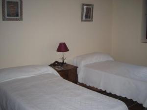 two beds in a hotel room with a lamp on a table at Casa Rural Los Boteros in Pesquera de Duero