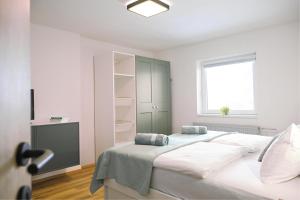 a white bedroom with a large bed and a window at Red Maple Apartments in Maribor +11 photos