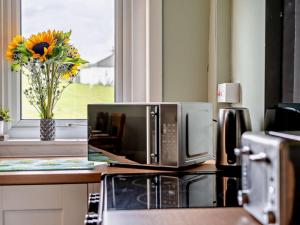 a kitchen counter with a microwave and a vase of flowers at 2 Bed in Carluke oc-95359 in Carluke