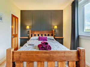 a large wooden bed with a purple towel on it at 2 Bed in Carluke oc-95359 in Carluke
