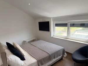 a white bedroom with a bed and a window at Apartment Lasta Medulin in Medulin