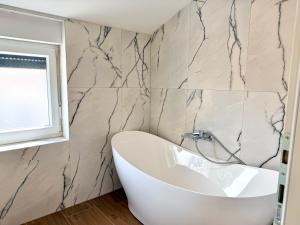 a bathroom with a white tub and a marble wall at Apartment Lasta Medulin in Medulin +35 photos