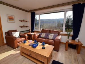a living room with leather furniture and a large window at 3 Bed in Inverness oc-in633 in Balnain