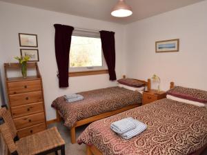 a room with two beds and a dresser and a window at 3 Bed in Inverness oc-in633 in Balnain