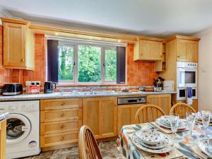 a kitchen with wooden cabinets and a table with chairs at 3 Bed in Keswick oc-sz047 in Threlkeld