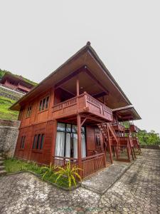 a wooden house with a balcony and a staircase at Lembah Indah Malang in Gendogo