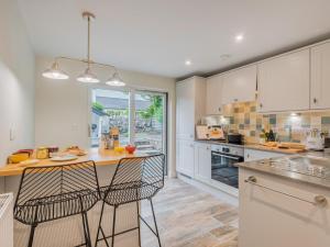 a kitchen with white cabinets and a island with two chairs at 1 Bed in Grange-over-sands oc-78659 in Cartmel