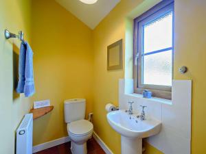 a yellow bathroom with a toilet and a sink at 2 Bed in Strontian oc-ca046 in Scotstown +12 photos