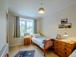 a bedroom with a bed and a dresser and a window at 2 Bed in Strontian oc-ca046 in Scotstown