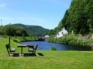 a picnic table and two chairs next to a river at 1 Bed in Lochgilphead oc-ca304 in Lochgilphead