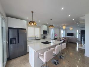a kitchen with white cabinets and a kitchen island with bar chairs at Casa Sandra in Tazacorte