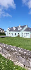 a white house with a stone wall in front of it at Dubhlinn House Accommodation in Doolin