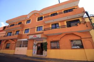 an orange building with a balcony on a street at Hotel Isabel I in Oaxaca City