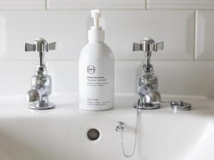 a white bottle of soap on a sink with two faucets at 1 Bed in Sedbergh oc-g0182 in Milnthorpe +16 photos