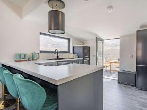a kitchen with a sink and a counter with chairs at 3 Bed in Kinlochleven oc-87130 in Kinlochleven