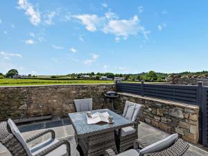 a patio with a table and chairs on a stone wall at 2 Bed in Grange-over-sands oc-89206 in Cartmel
