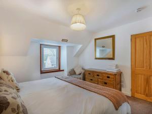 a bedroom with a bed and a dresser and a mirror at 4 Bed in Ballindalloch oc-46162 in Tomintoul