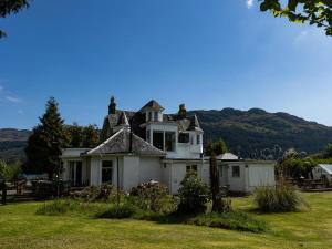 an old house in a field with mountains in the background at 5 Bed in Lochgoilhead oc-ca279 in Carrick