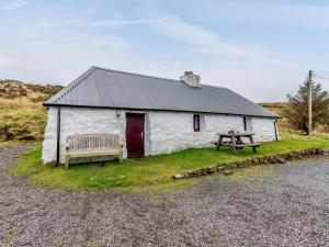 a small white building with a bench and a table at 1 Bed in Isle Of Skye oc-ca073 in Glendale