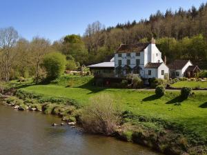 a large white house on a hill next to a river at 1 Bed in Telford oc-73319 in Buildwas