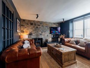 a living room with a leather couch and a fireplace at 3 Bed in Stranraer oc-77308 in Portpatrick