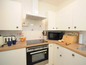 a kitchen with white cabinets and a stove top oven at 2 Bed in Fort Augustus oc-in637 in Fort Augustus